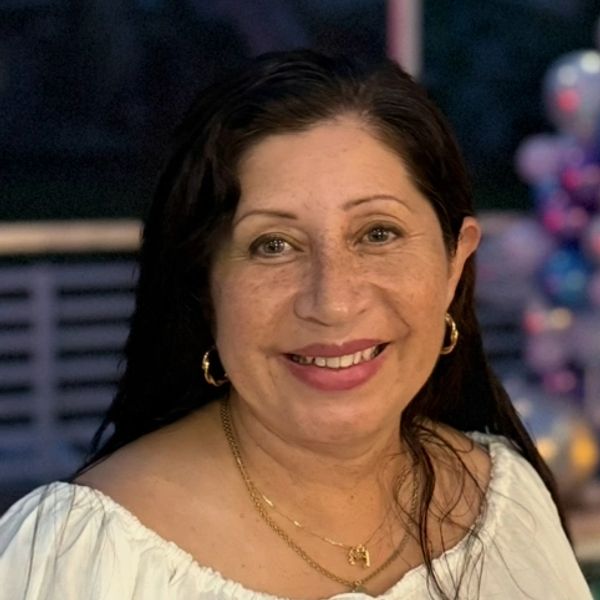 Smiling woman with long dark hair wearing a white blouse and gold jewelry — Rosario Garcia Fino, Clinical Director at Flourish Counseling